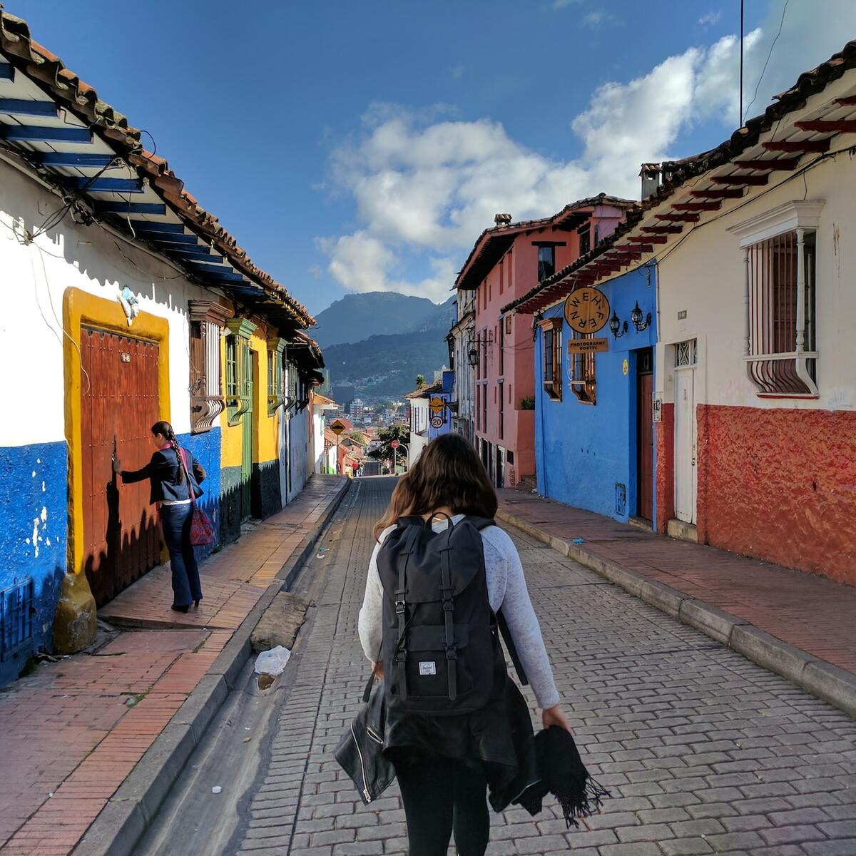 A girl wearing a backpack walks through La Candelaria, Bogota