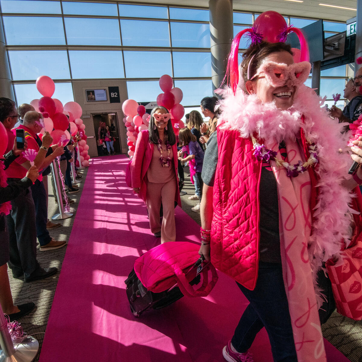 Breast cancer survivors walk a pink runway after the Delta Breast Cancer One charter flight arrived at its destination.