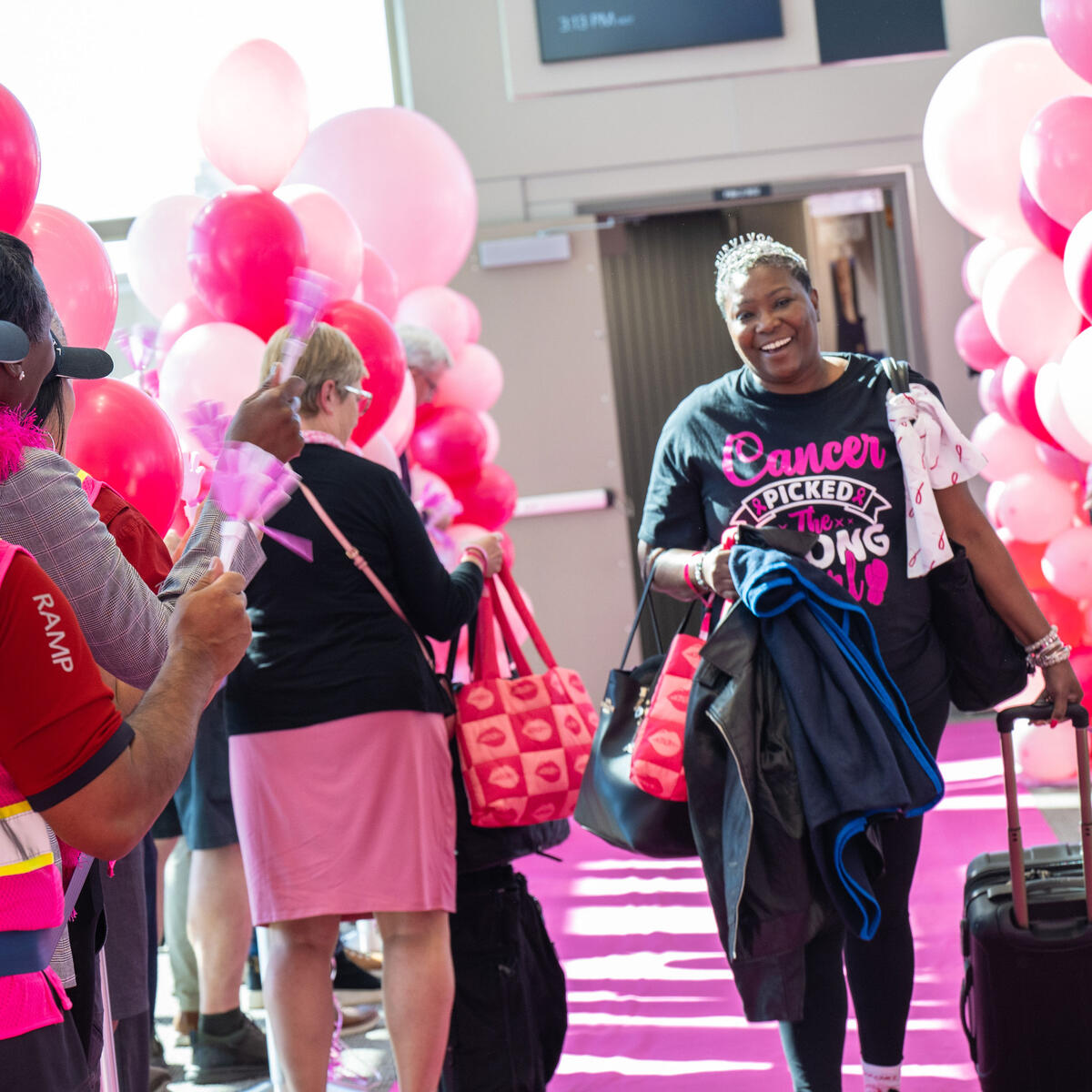 A breast cancer survivor walks down a pink runway after disembarking the Breast Cancer One charter flight.