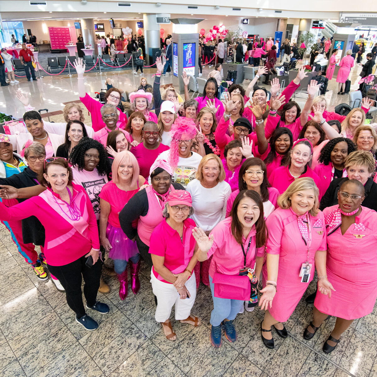 A group of breast cancer survivors pose for a group photo before boarding Delta's Breast Cancer One charter flight.