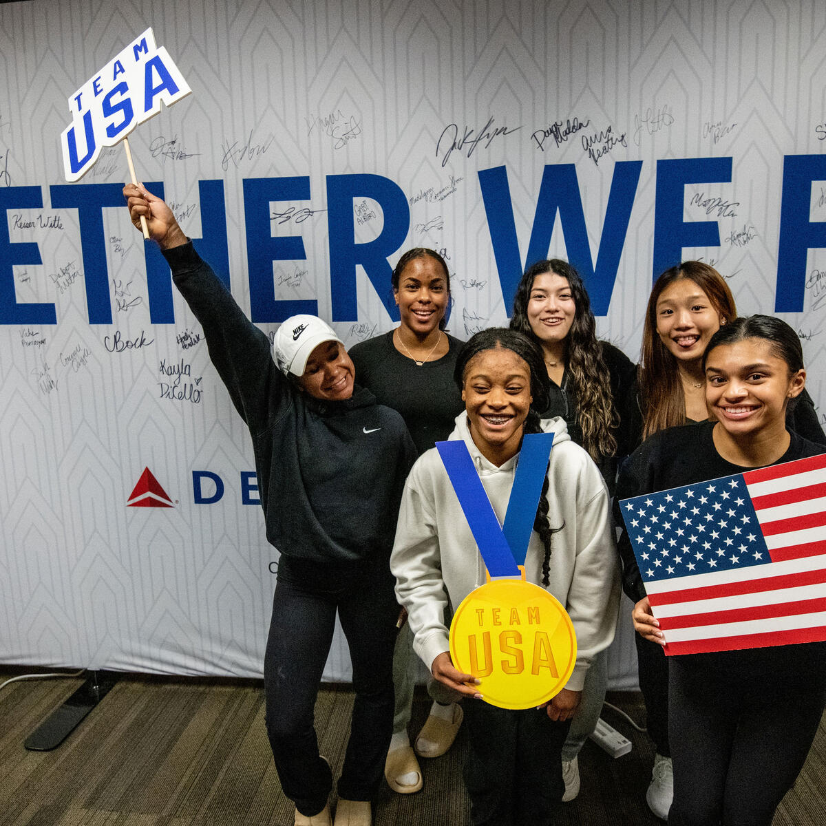 Team USA athletes pose in front of a wall in Delta's customized athlete lounge in the ATL International Terminal.