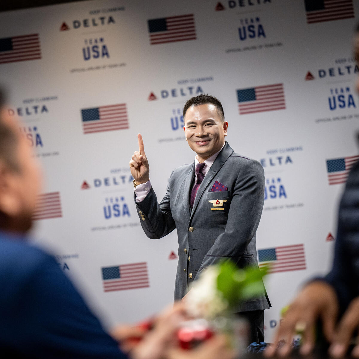 A Delta flight attendant poses in front of a Team USA wall in the customized athlete lounge in the ATL International Terminal.