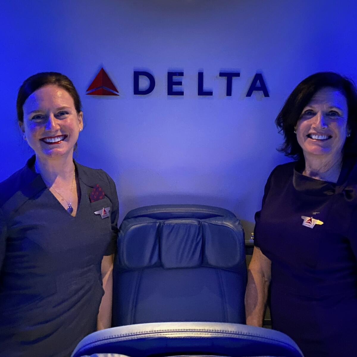 A mother and daughter duo who have nearly 30 years of combined service at Delta pose for a photo onboard a plane.