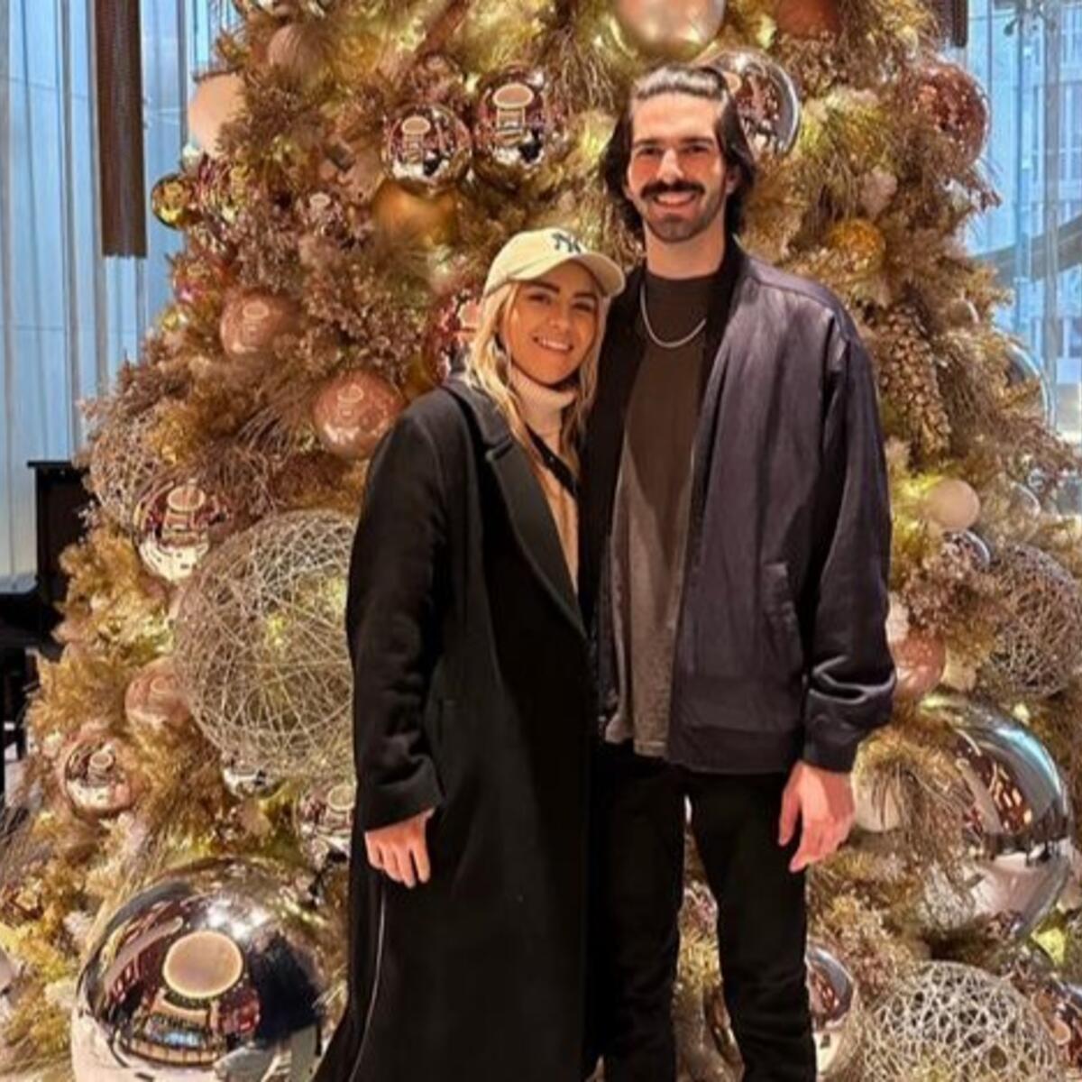 Delta customers Paige and Ian, who met in a Delta Sky Club, pose in front of a Christmas tree.