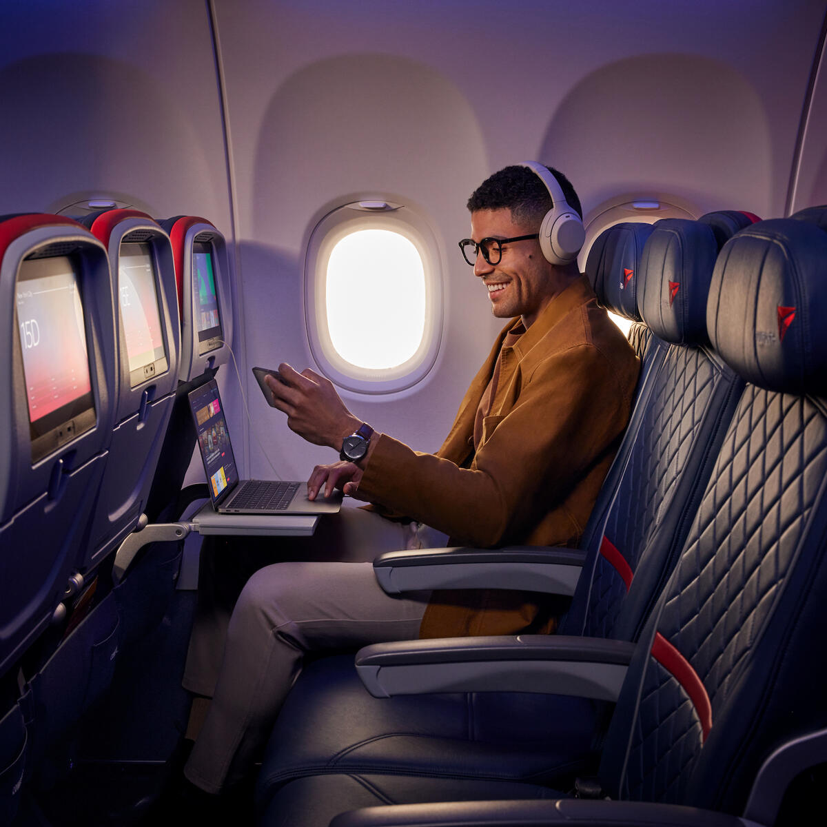 A customer uses Delta's fast, free Wi-Fi on board on their smart phone and laptop.