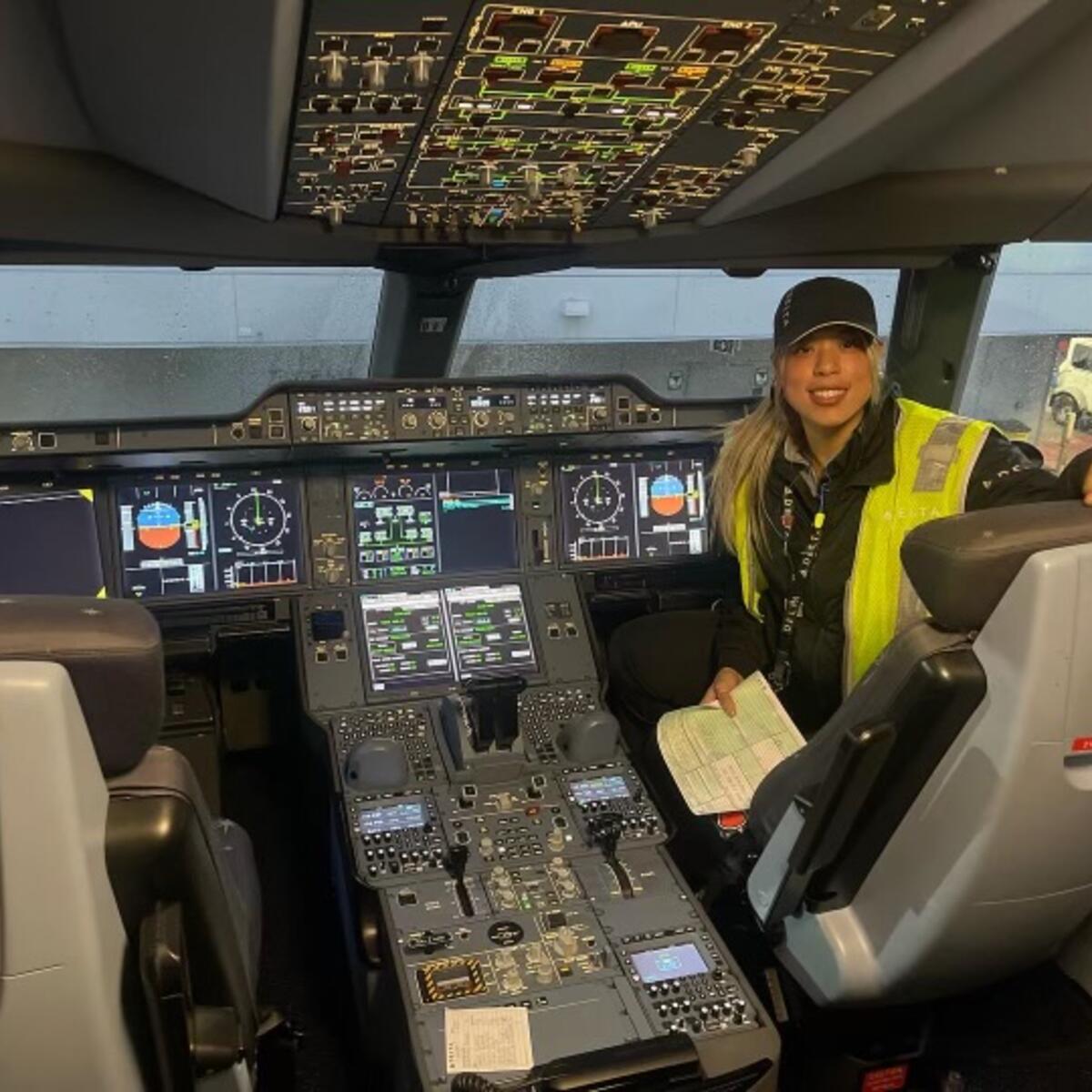 Delta TechOps employee Jessie Hekimian sits in the flight deck of an airplane.