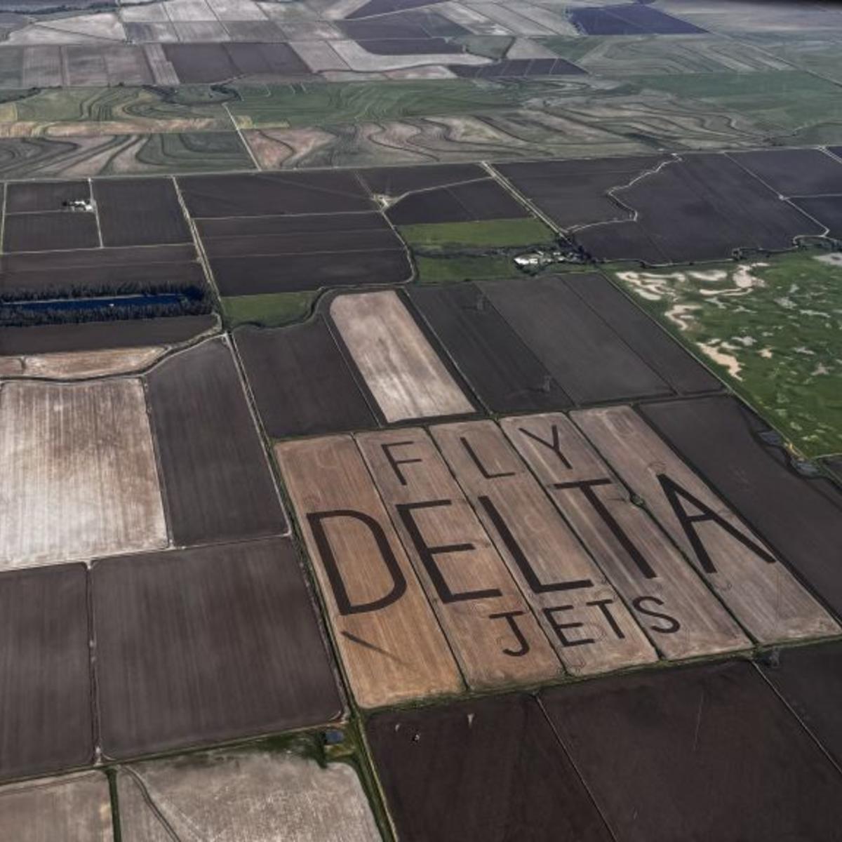 An aerial view of "Fly Delta Jets" carved into the field of a rice farm