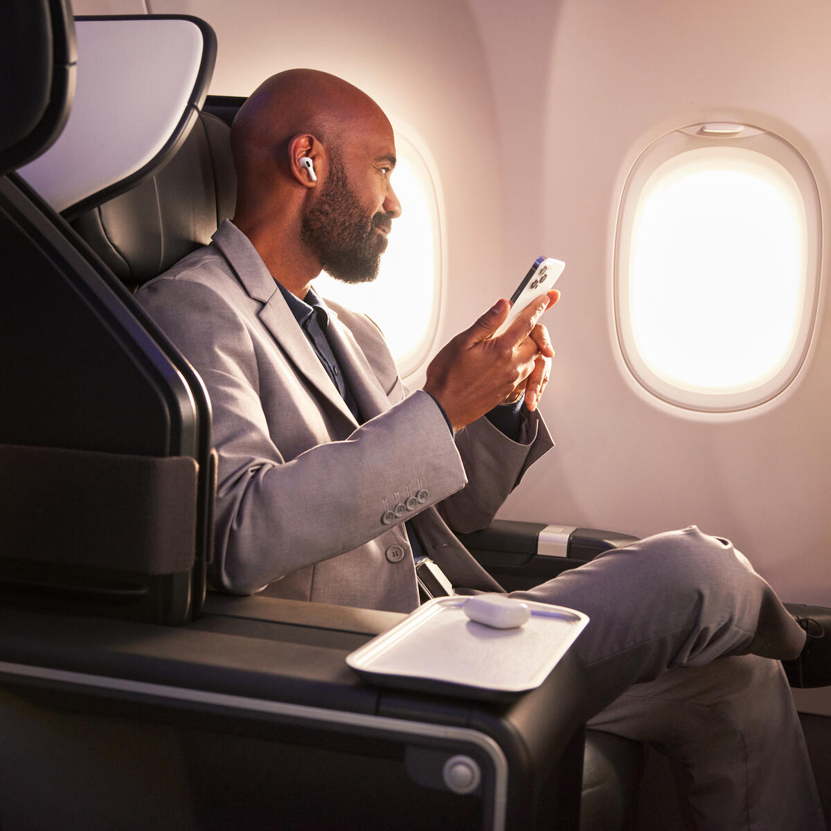 A Delta customer sits in Delta's First Class cabin, holding their phone.