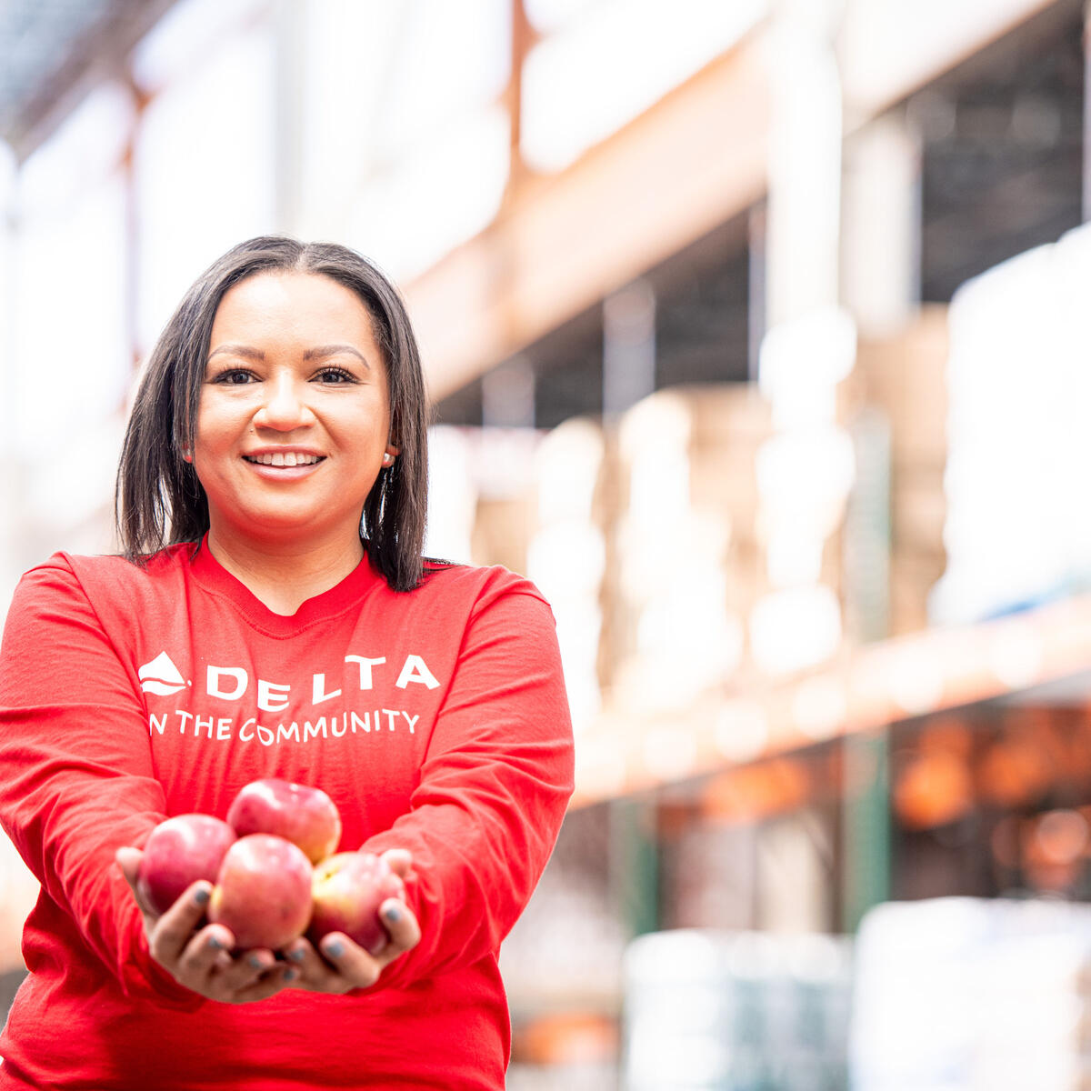 A Delta volunteer holds apples in their hand