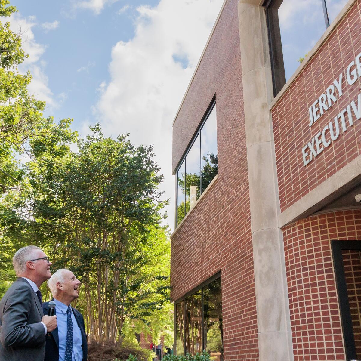 Delta CEO Ed Bastian and former Delta CEO Jerry Grinstein look up at a building.