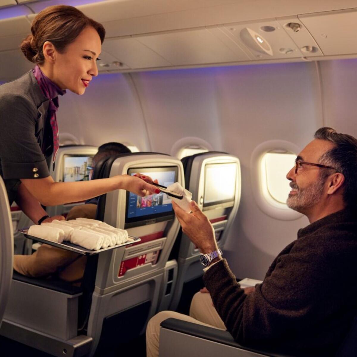 A Delta flight attendant offers a customer a hot towel.