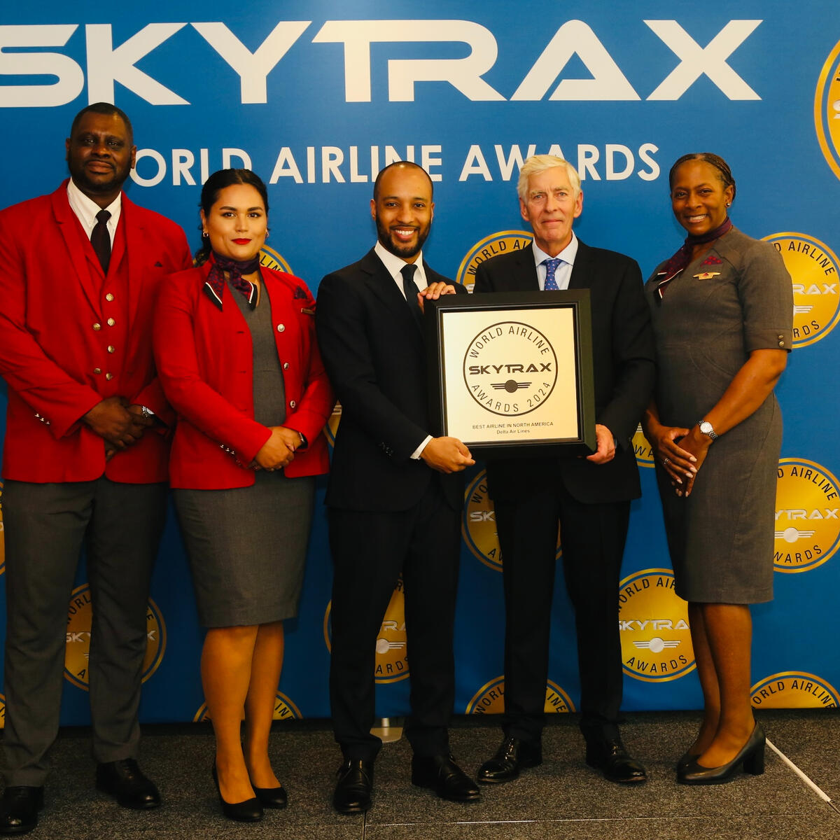 Delta employees accept a Skytrax World Airline Award from Edward Plaisted, the CEO of Skytrax.