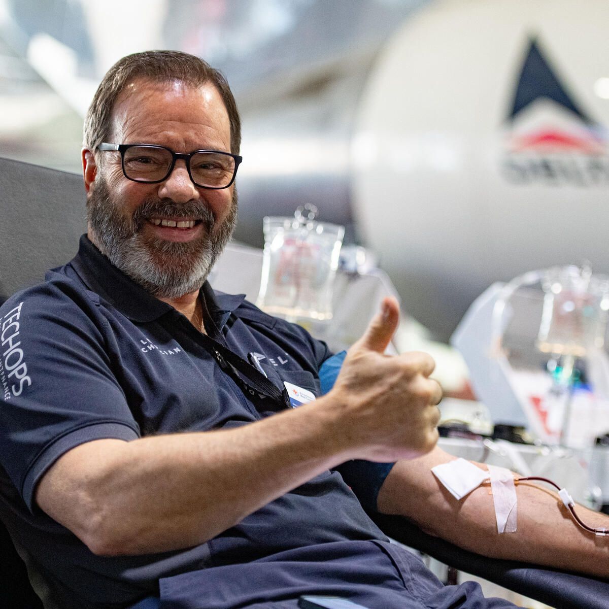 A Delta TechOps employee gives a thumbs up while donating blood.