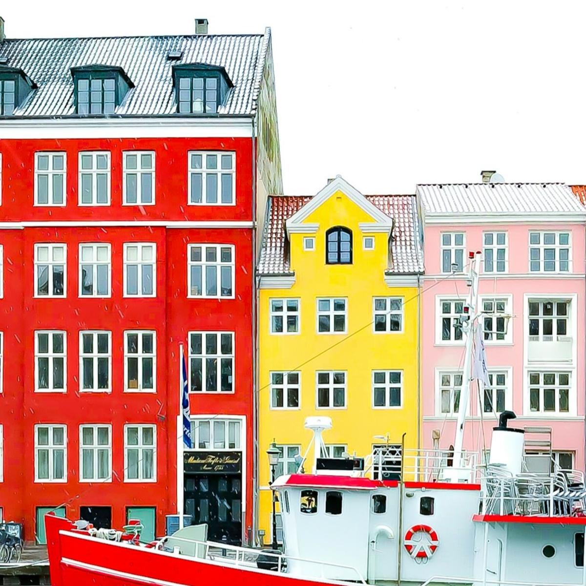 Nyhavn district with boats on water canal and colorful row of old houses in Copenhagen, Denmark