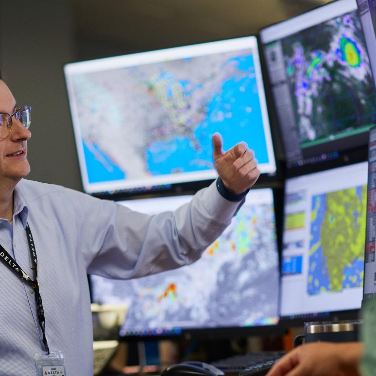 A meteorologist sits in front of multiple screens inside Delta's Operations & Customer Center