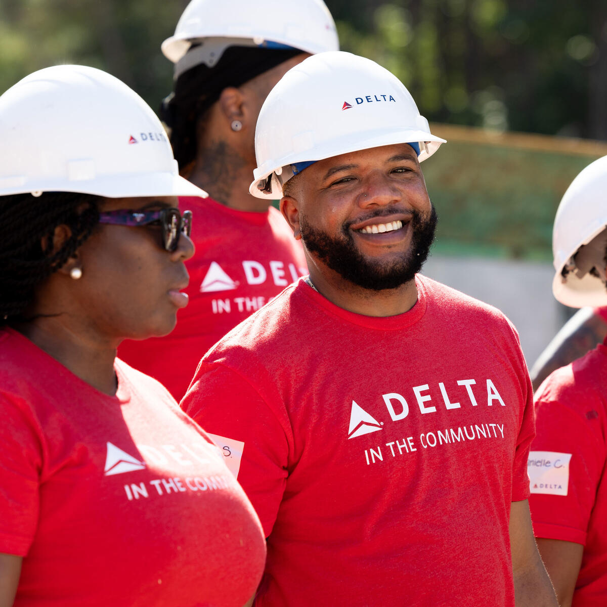 Smiling Delta volunteer in red shirt and white hard hat