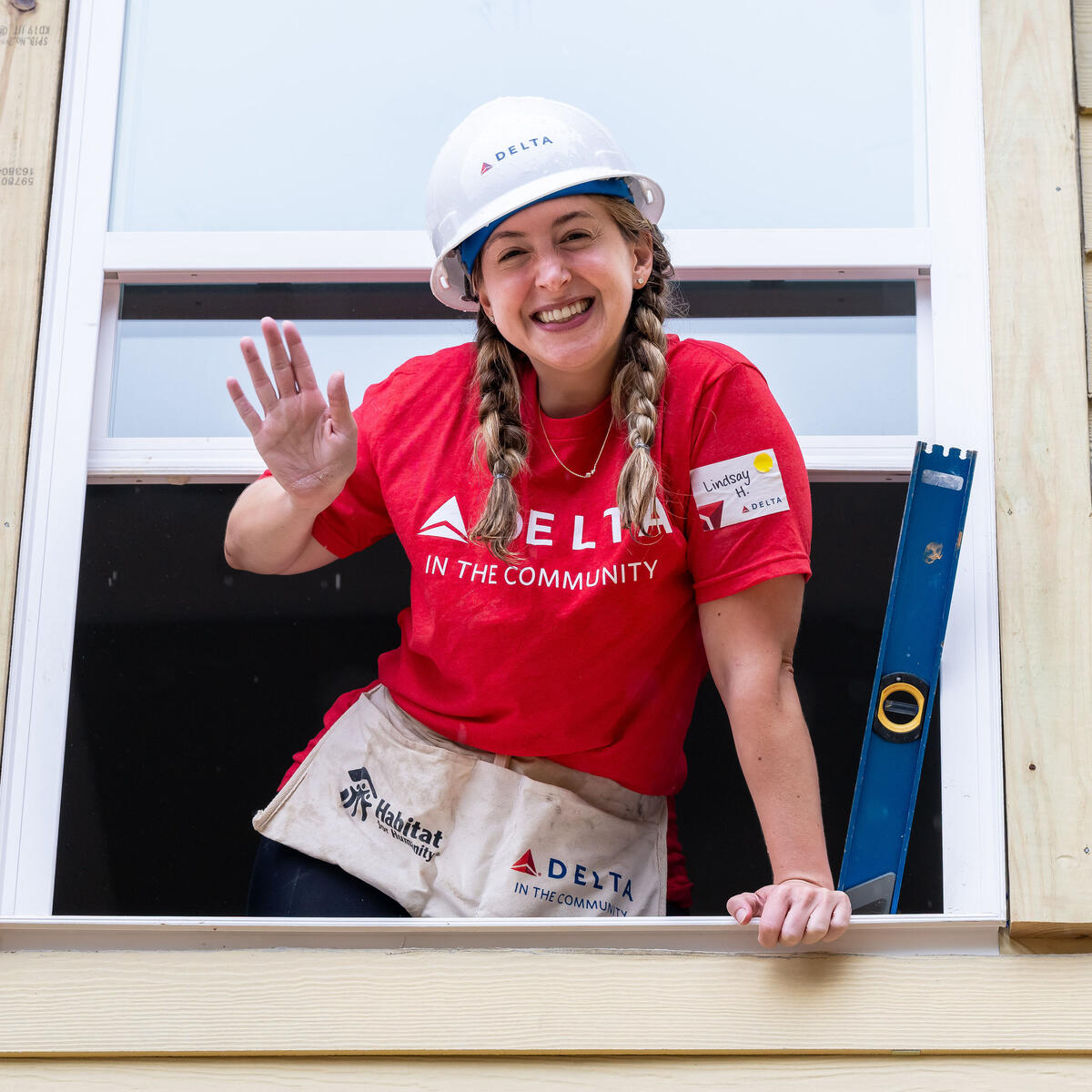 Delta Atlanta Habitat for Humanity volunteer standing in window, waving and smiling