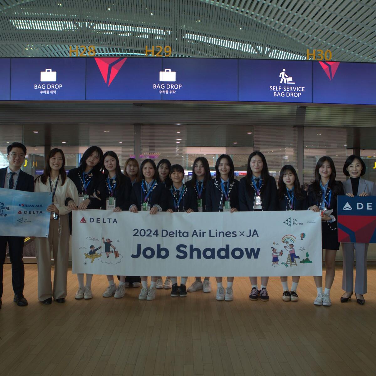 High school students pose in ICN Airport to commemorate their job shadowing experience with Delta and Junior Achievement.
