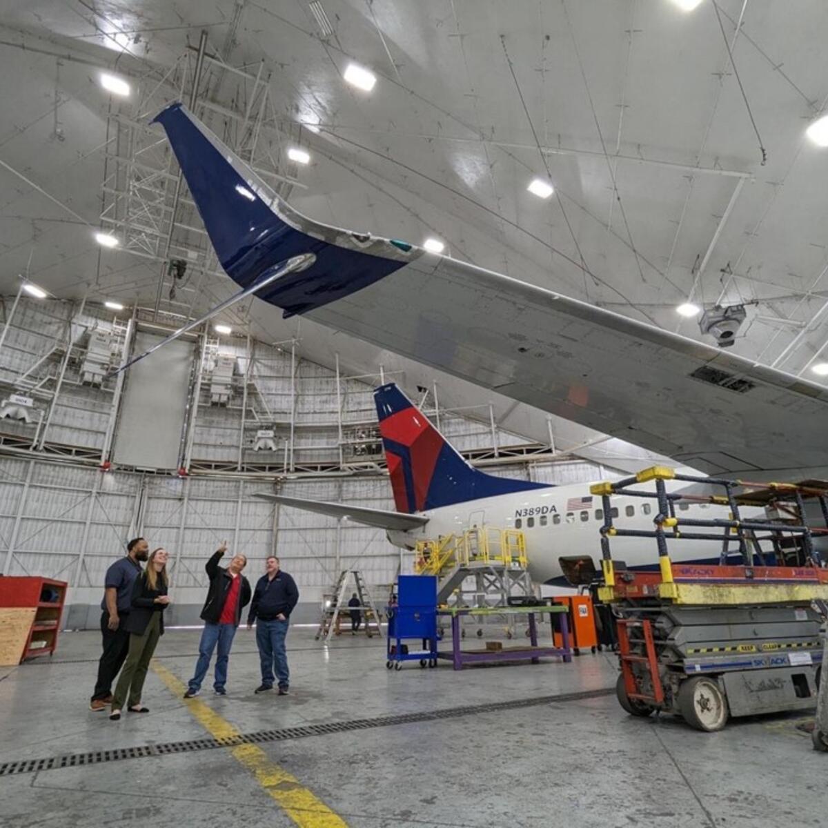 Group of people looking up at airplane winglet.