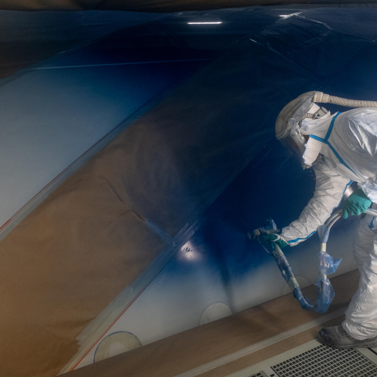 A Delta employee paints the body of an aircraft for Delta's Centennial livery.