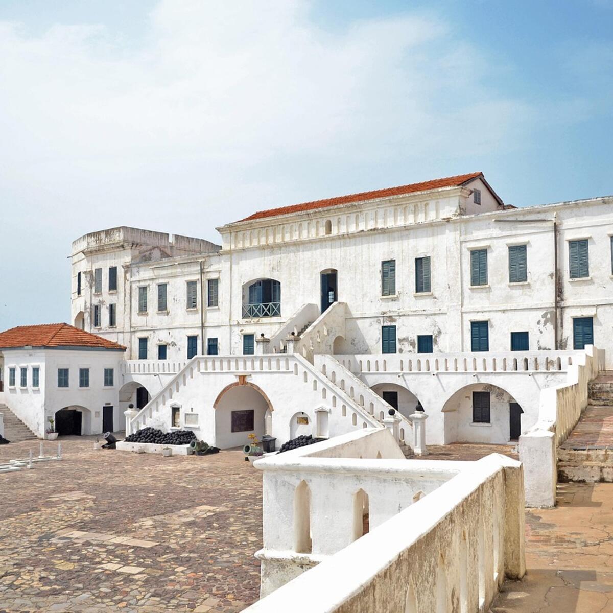 Ghana's Elmina Castle beneath a blue, lightly cloudy sky.