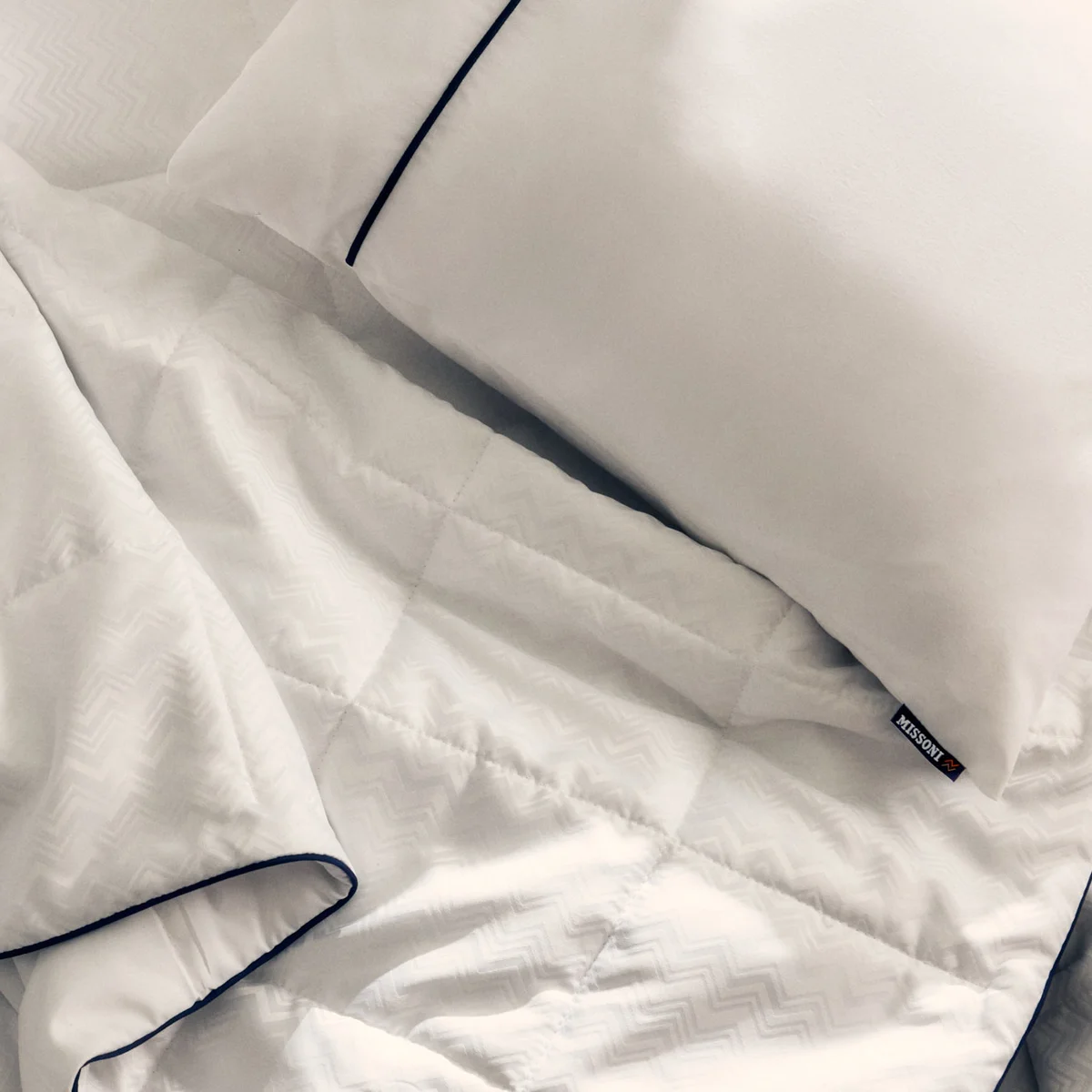 El nuevo juego de cama de Delta One incluye el edredón Missoni y una almohada blanca para dormir, con un sutil y elegante diseño en zigzag de Missoni y detalles en azul marino.