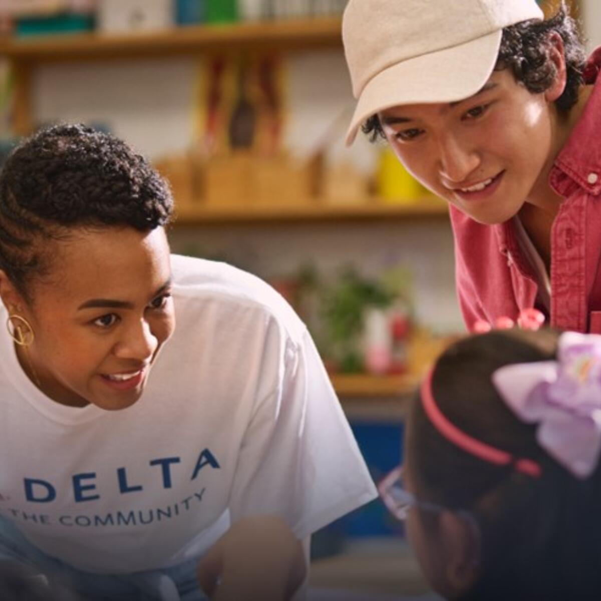 Delta employee volunteer smiling while interacting with a young girl.
