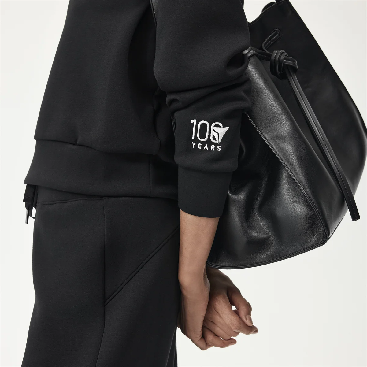 Profile shot of woman wearing black spanx outfit embroidered with Delta Centennial logo.