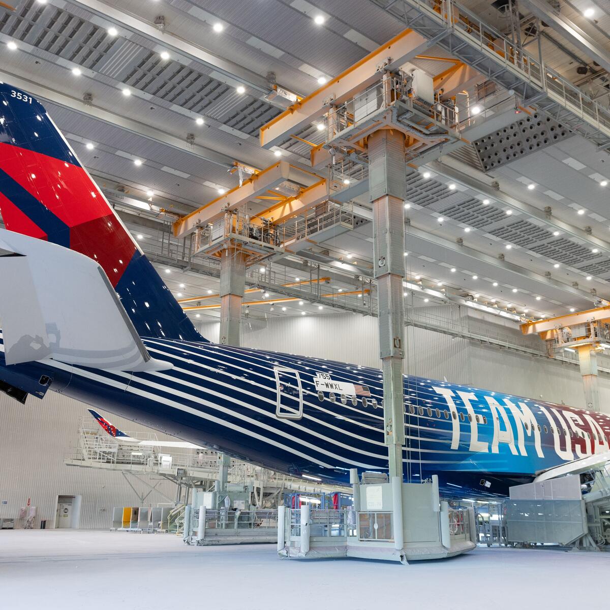 Delta plane with Team USA livery parked in a well-lit hangar.