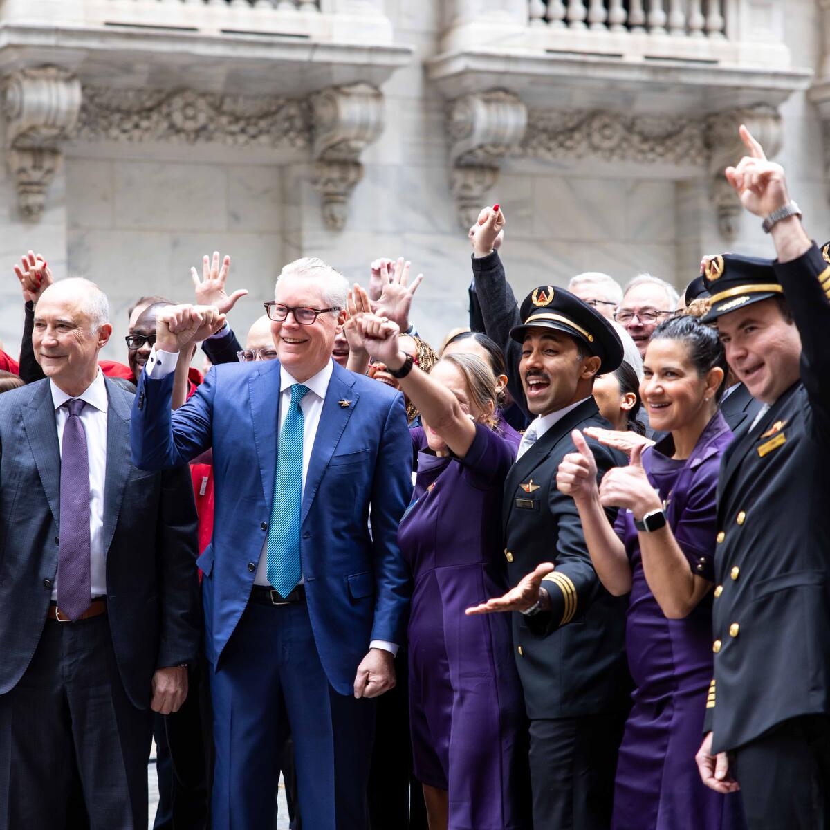 Group photo of Ed and Delta employees cheering outside of the NYSE building