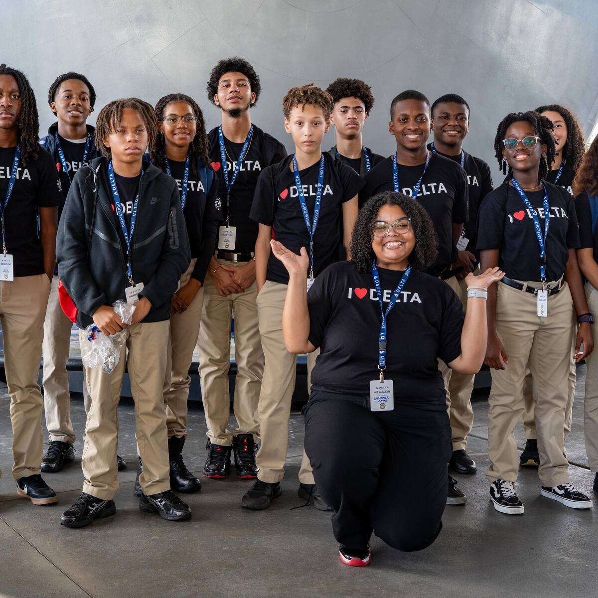DREAM flight participants posing for in front of a large metallic structure wearing matching black Delta t-shirts.