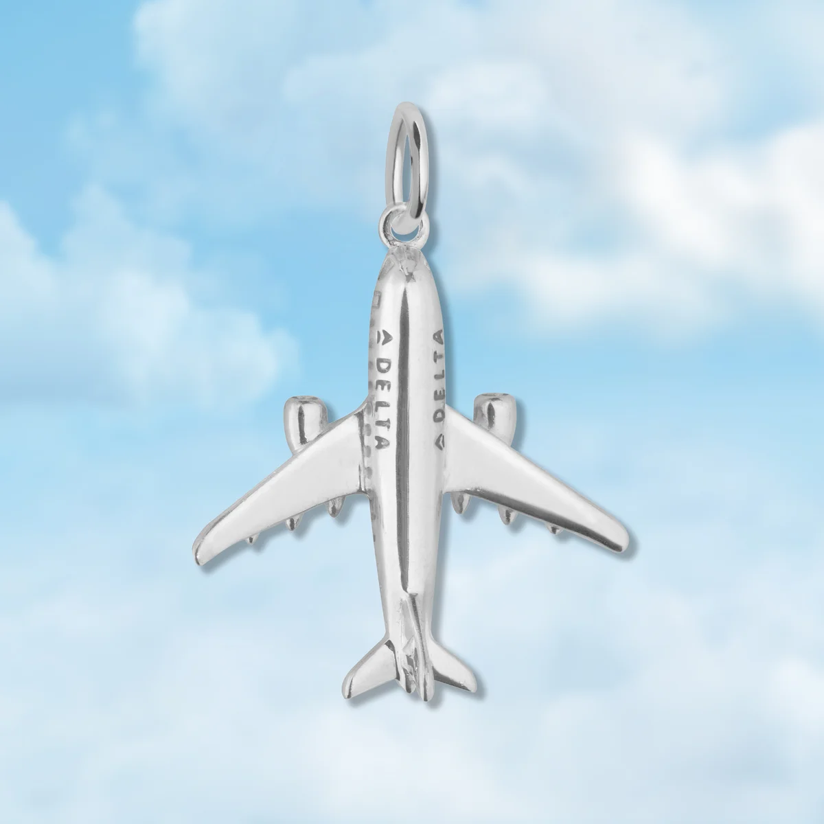 Silver plane charm on blue cloud background. 