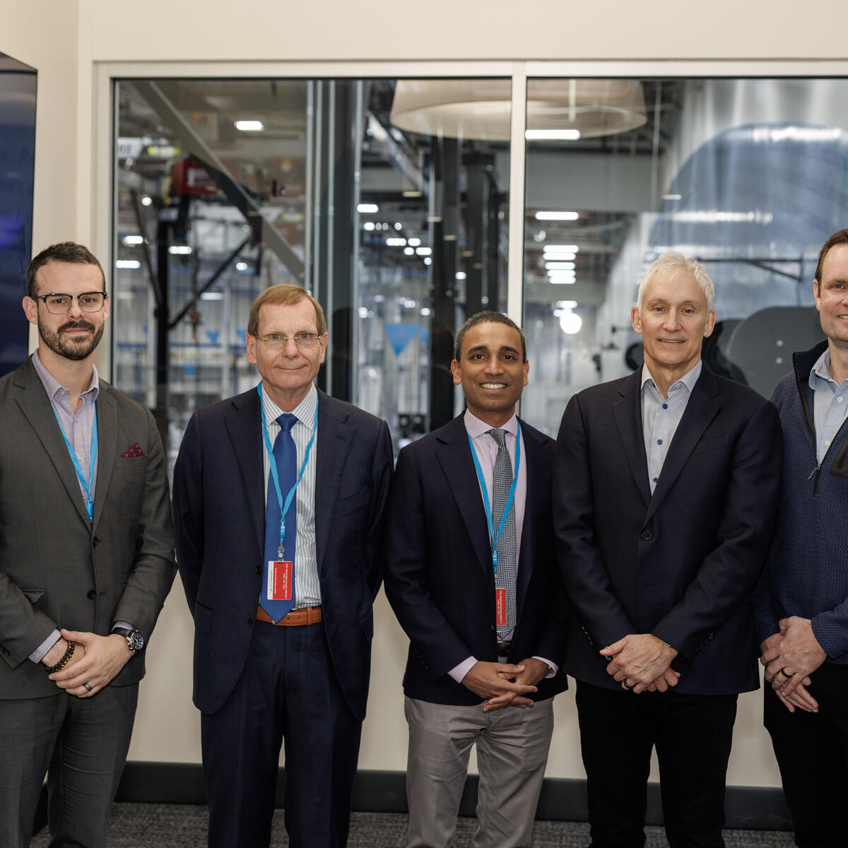 Members of Delta and Amazon Leo teams pose for a picture with factory as backdrop.