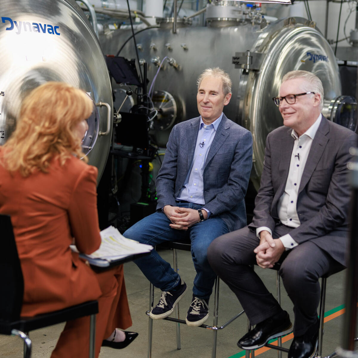 Ed Bastian and Andy Jassy sitting down during media interview with Amazon Leo factory in background.