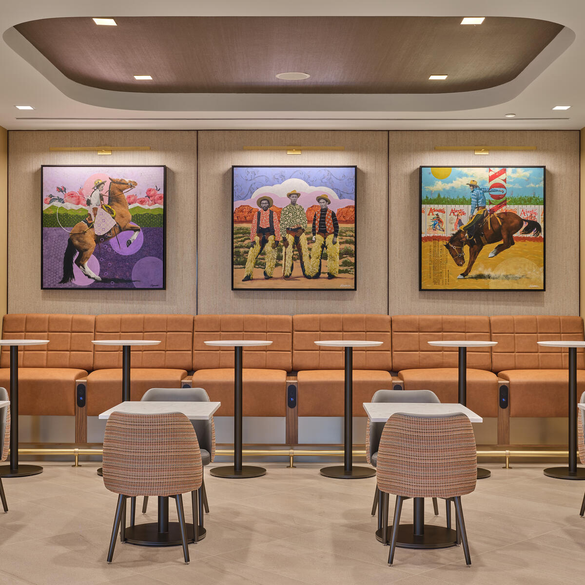 Seating nook with woven chairs, high-back bench seating, small tables and three colorful art pieces displayed on the wall