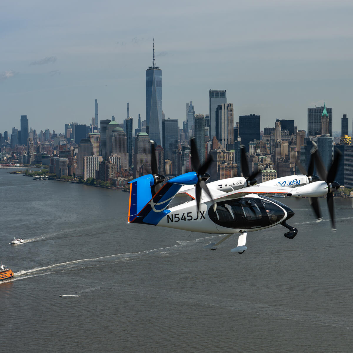 Joby electric air taxi flying over the Hudson River with the New York City skyline in the background.