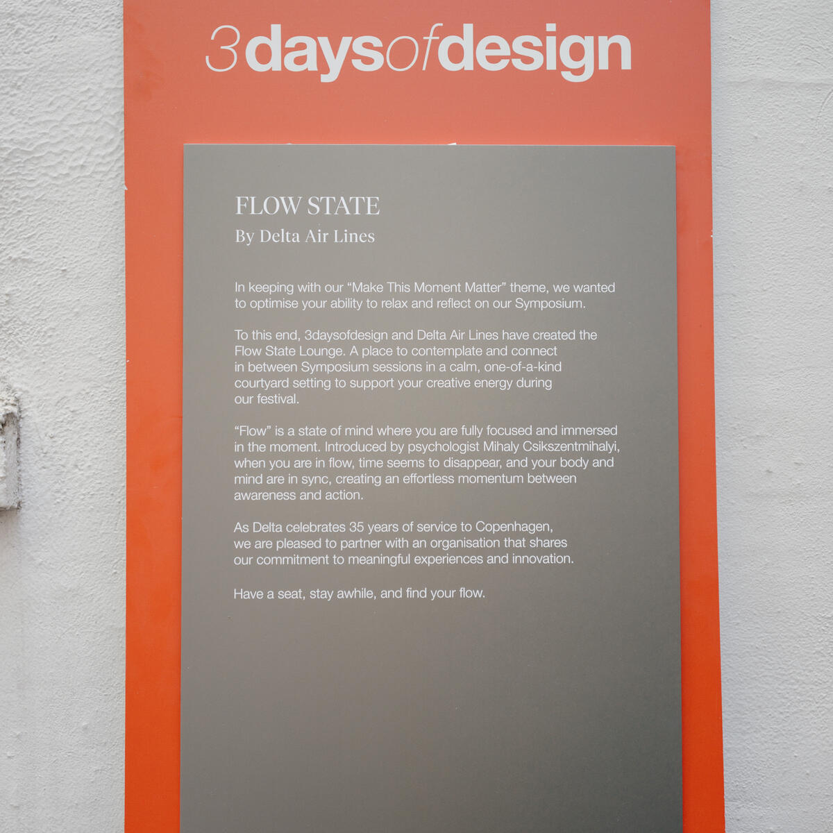 Poster on a wall reading “3daysofdesign” with a “Flow State by Delta Air Lines” description and event program details below.