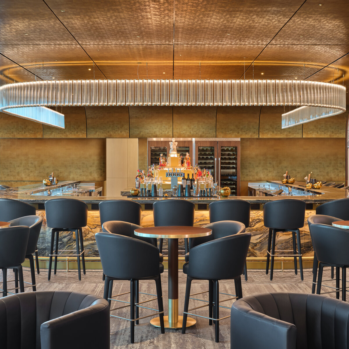 Upscale airport lounge bar with modern seating, marble accents, and a large illuminated chandelier overhead.