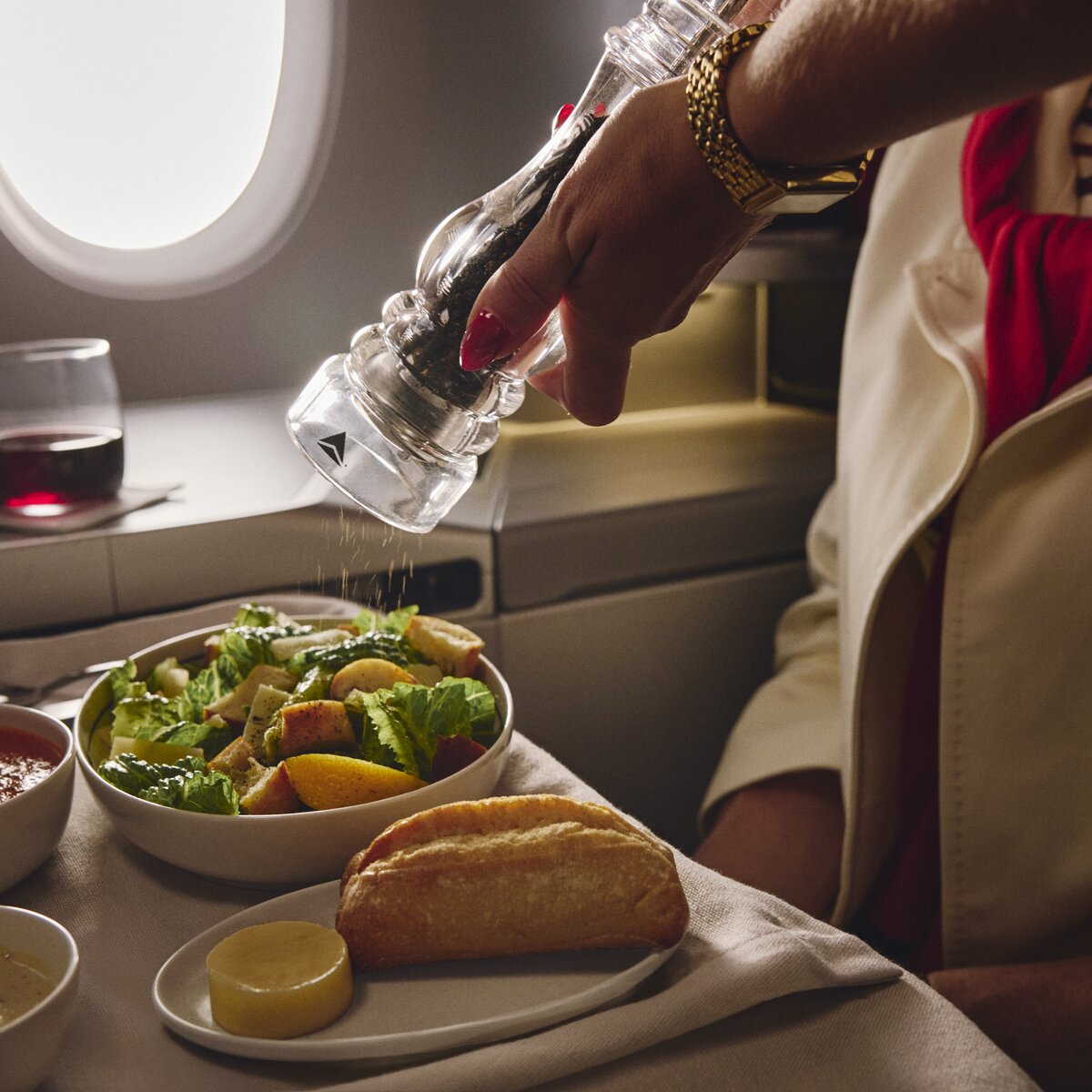 Fresh salad, soup, bread, and wine served on a Delta One dining tray table.