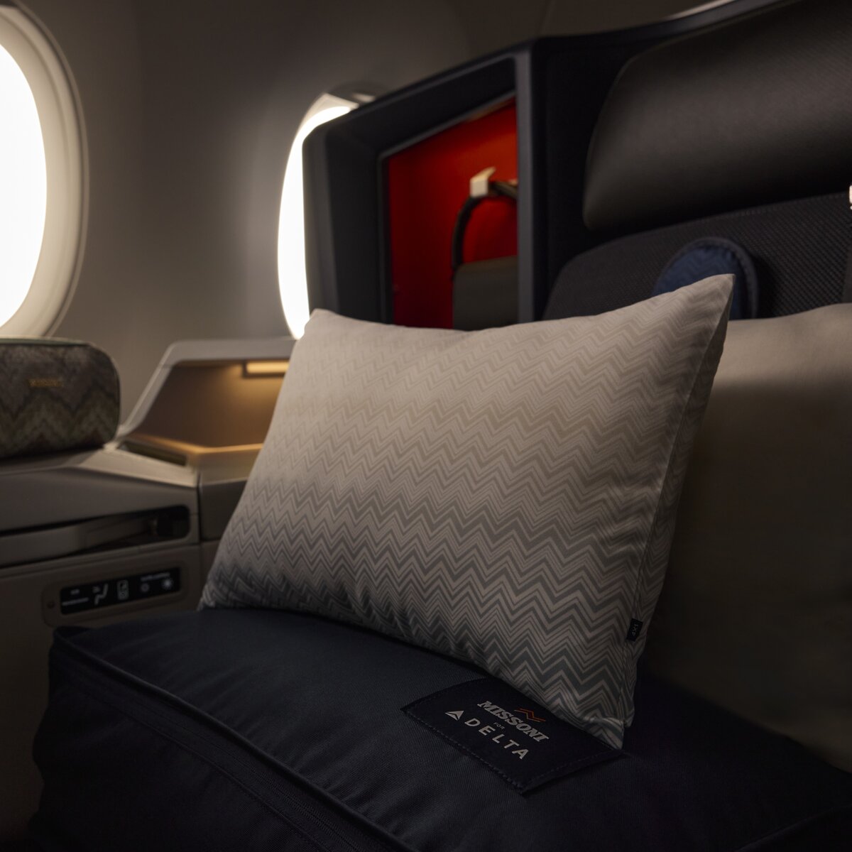 Delta One suite featuring premium bedding, pillows and an amenity kit by the window.