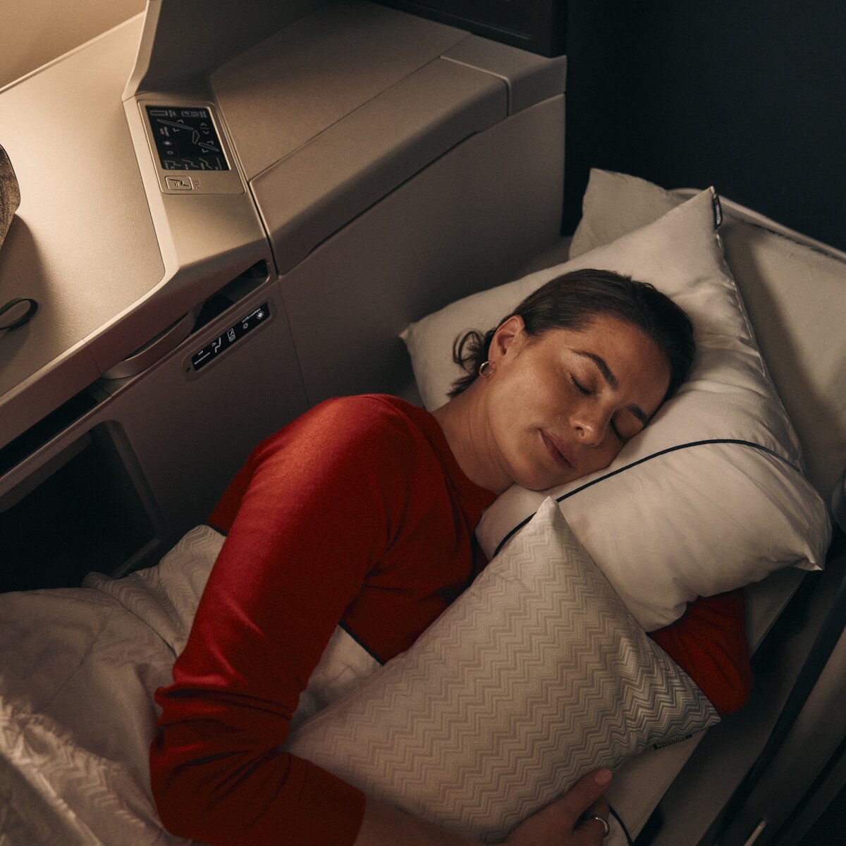 Customer resting in a lie-flat Delta One suite with bedding and pillow.