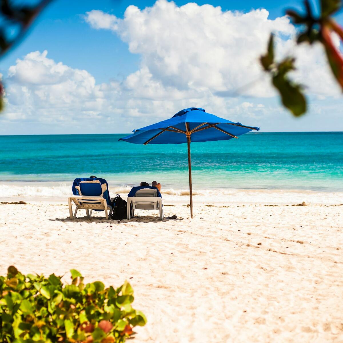 A couple sitting on lawn chairs on an umbrella in Barbados.