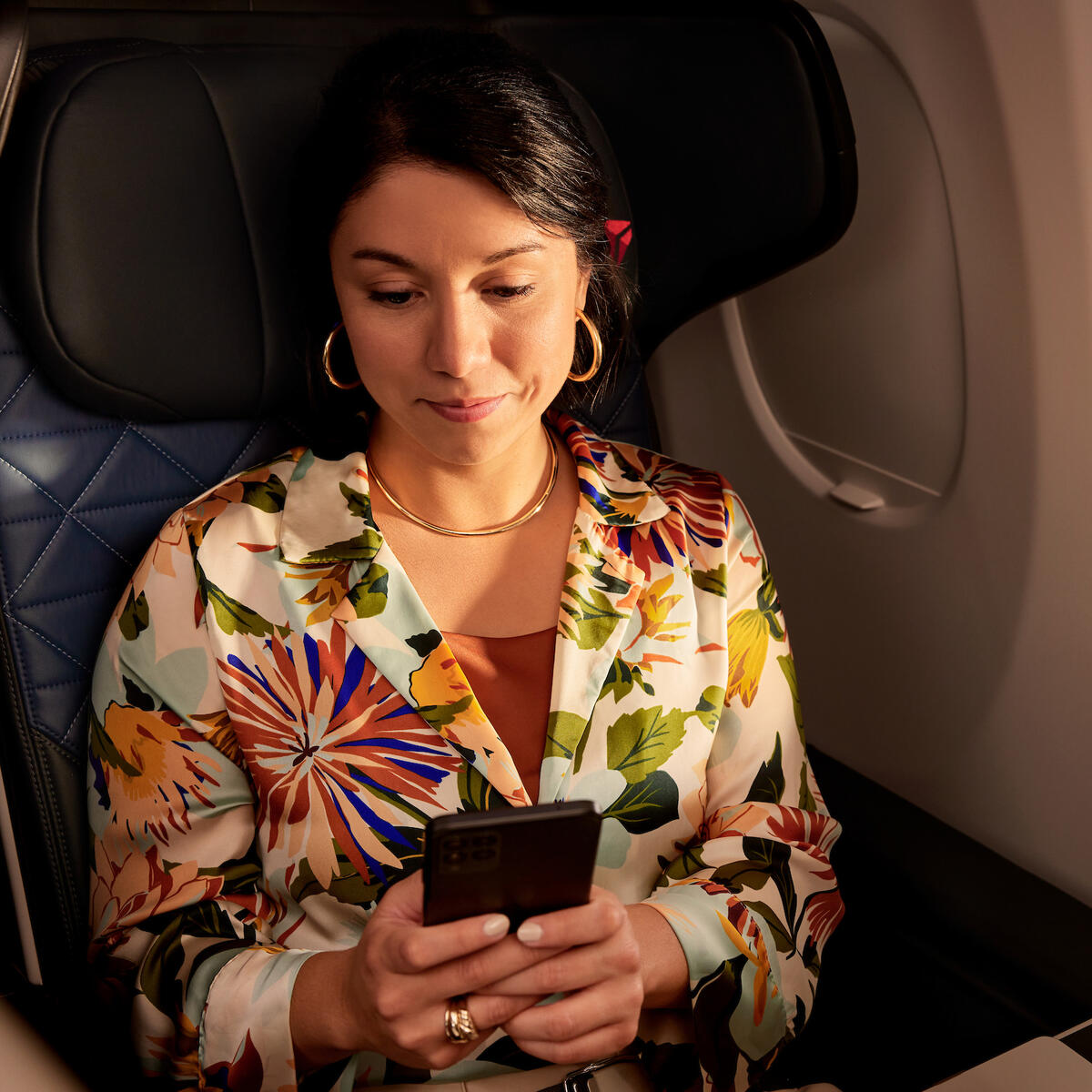 A customer seated on a Delta plane uses their mobile device.