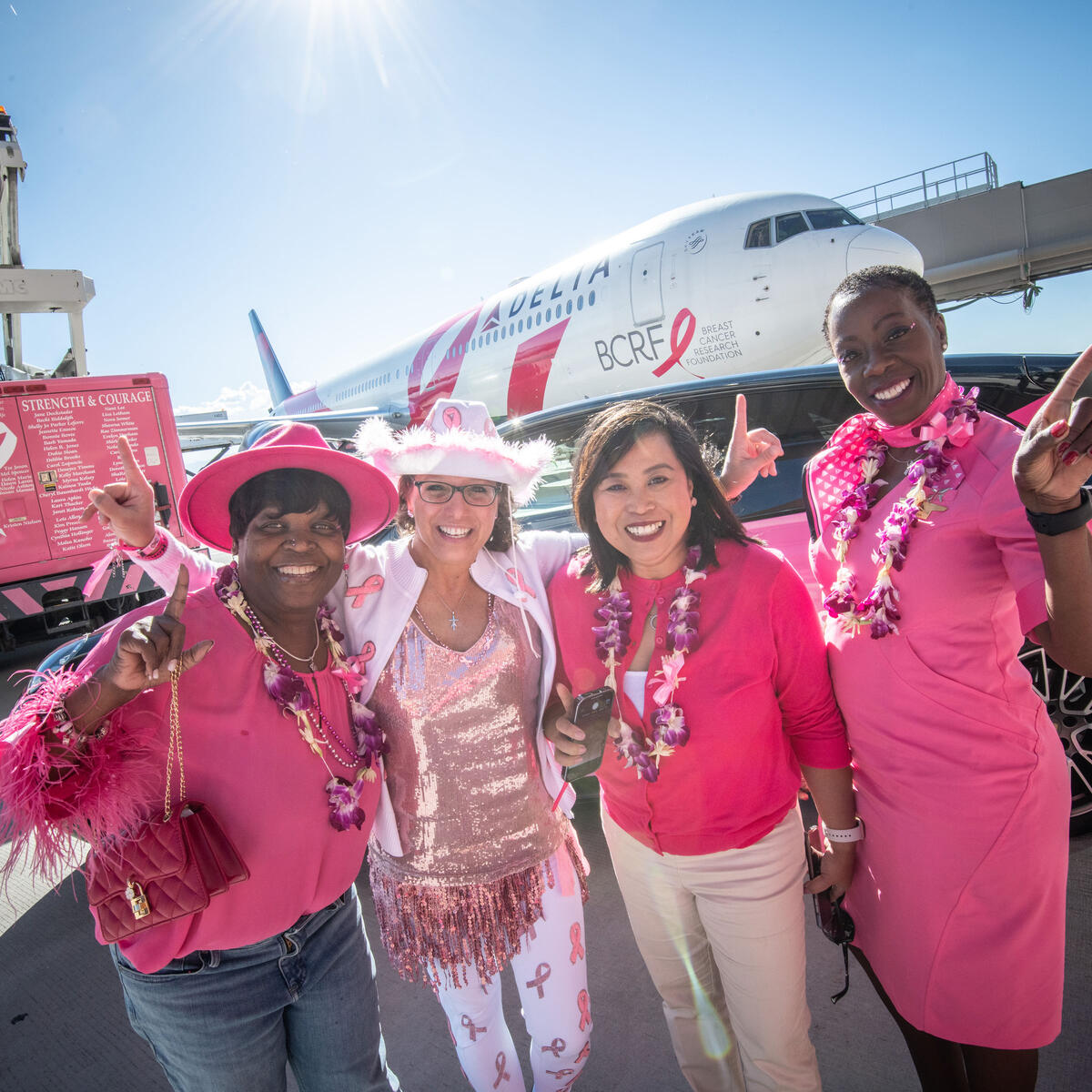 Delta people pose in front of the Breast Cancer One charter plane.
