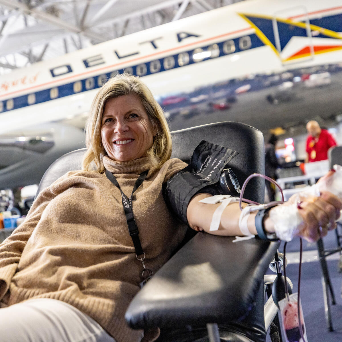 A woman sits in front of a Delta jet in the Delta Flight Museum, giving blood during one of Delta's many blood drives.
