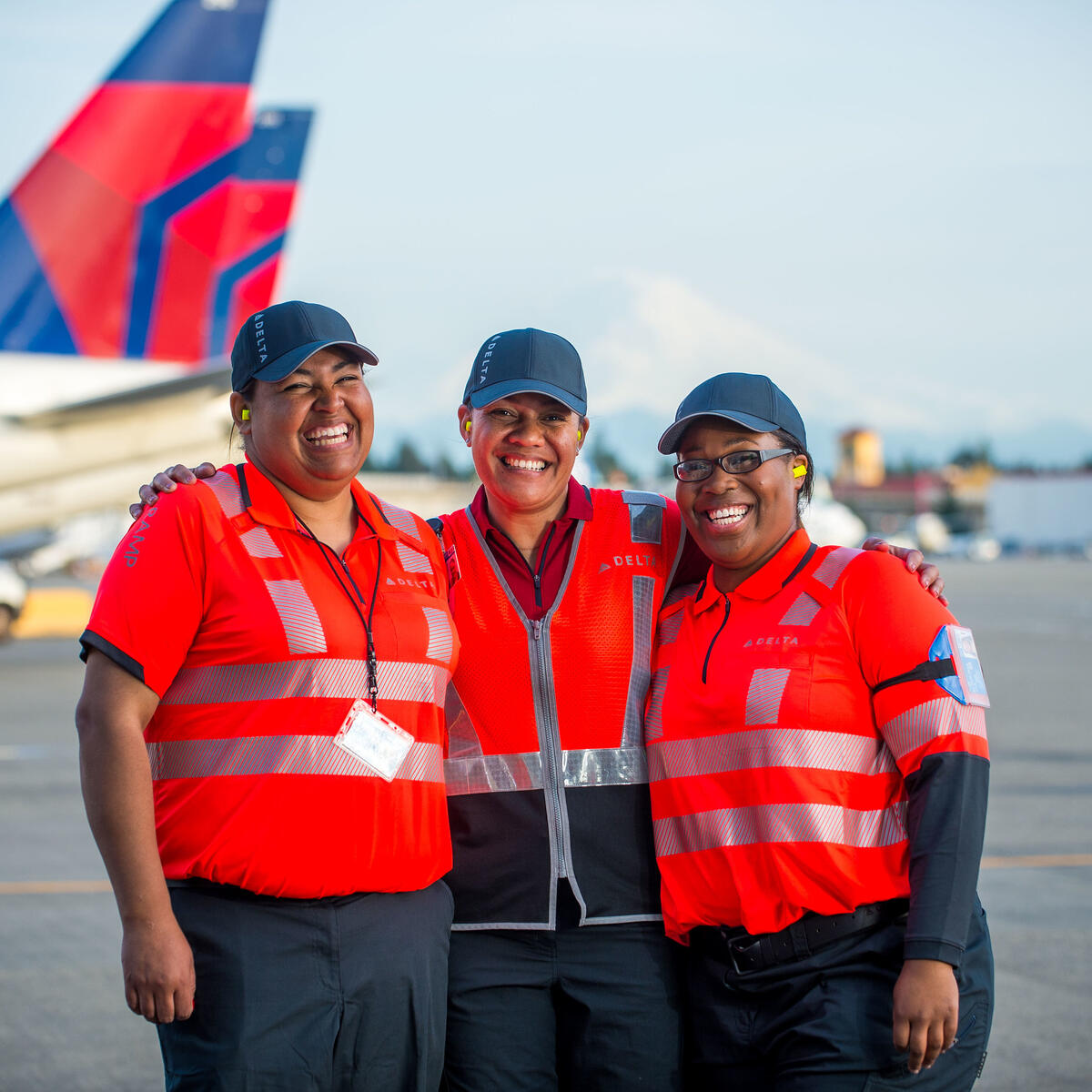 Three ramp agents stand in front of Delta aircraft at the Seattle-Tacoma International Airport.