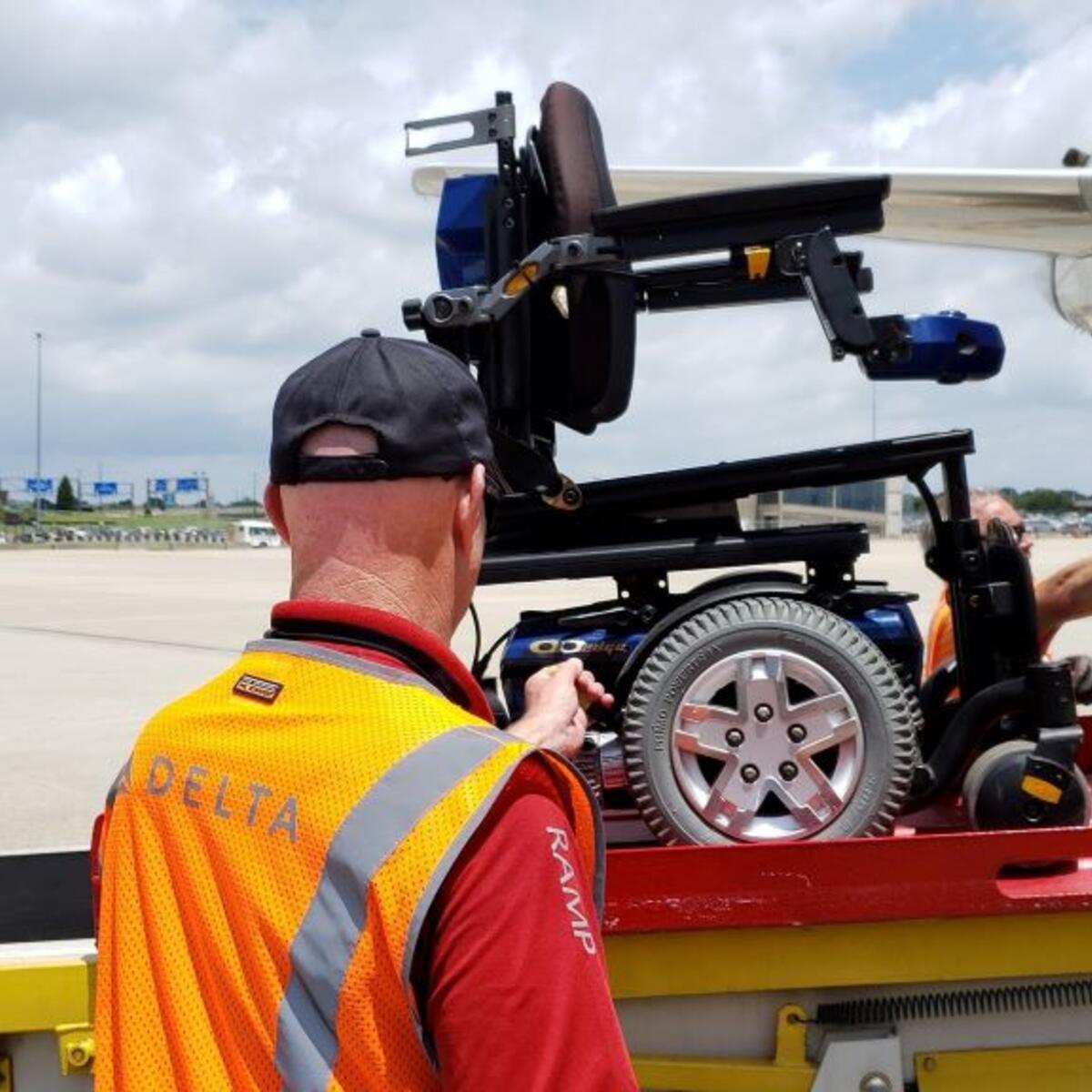 A Delta ramp agent loads a wheelchair onto a plane.
