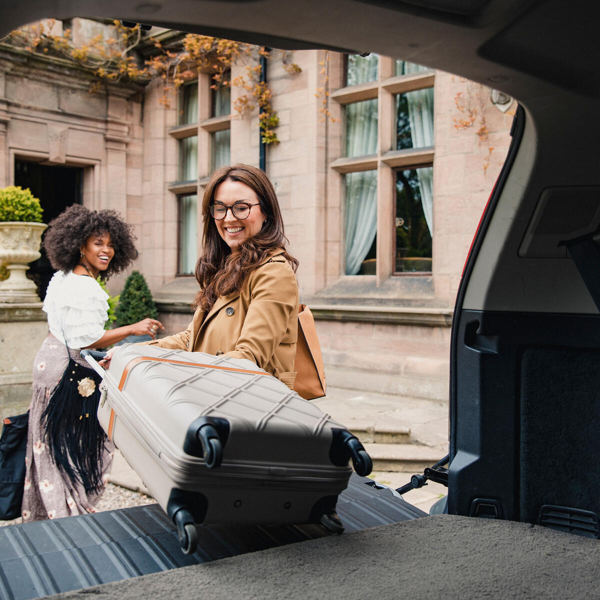 Two people unload suitcases from their vehicle in this stock photo taken in April 2019.