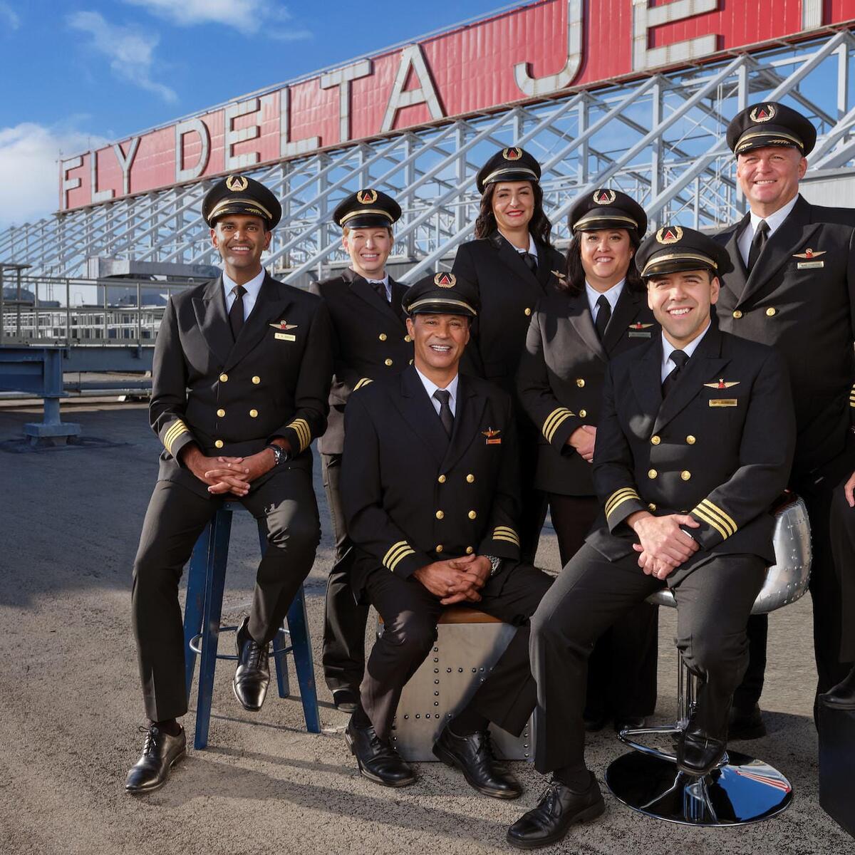 Group of eight Delta pilots gathered before historic Delta sign