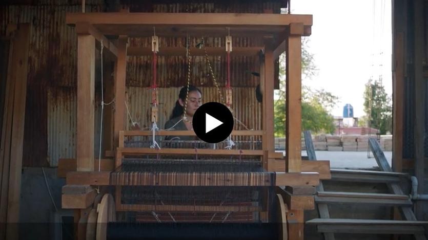 A woman works at a loom.